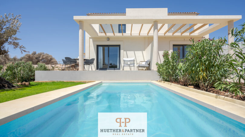 Außenansicht moderne Neubau-Villa in Cala Romàntica mit privatem Pool, Pergola-Terrasse und mediterranem Garten.