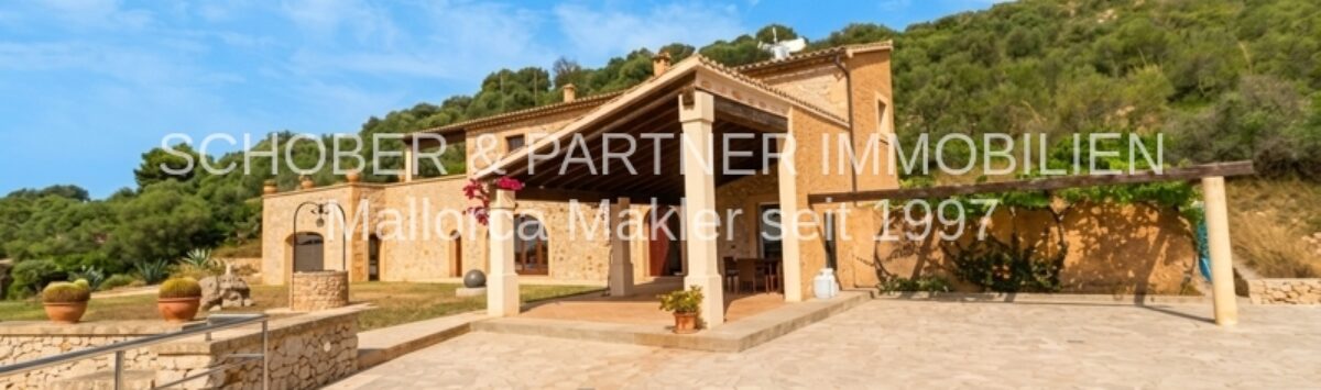 Finca in Son Carrió mit Pool, überdachter Terrasse und Natursteinmauern, eingebettet in grüne Hügellandschaft.