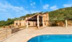 Finca in Son Carrió mit Pool, überdachter Terrasse und Natursteinmauern, eingebettet in grüne Hügellandschaft.