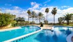 Spacious outdoor pool with palm trees and sea view of the exclusive residential complex in Son Servera, Mallorca