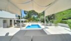 Überdachte Poolterrasse mit Sonnenliegen, modernem Swimmingpool und üppigem Garten der Villa in Santa Ponça.