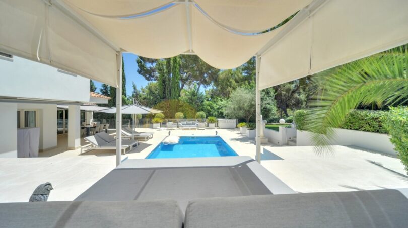 Überdachte Poolterrasse mit Sonnenliegen, modernem Swimmingpool und üppigem Garten der Villa in Santa Ponça.
