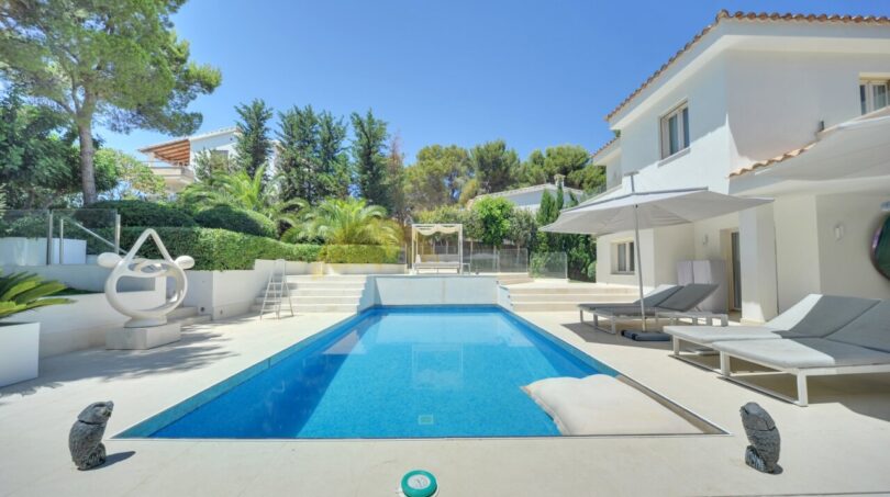 Moderner Pool mit Sonnenliegen und weißer Villa in Santa Ponça, umgeben von mediterranem Grün.
