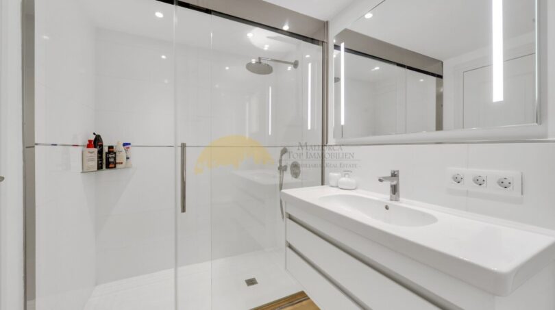 Modernes Badezimmer mit begehbarer Dusche, Doppelwaschbecken und hochwertiger Spiegelbeleuchtung