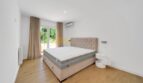 Helles Schlafzimmer der Villa in Santa Ponça mit Doppelbett, Holzboden, Klimaanlage und Zugang zur Terrasse.