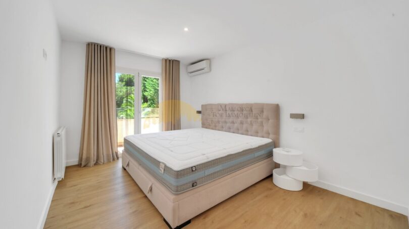 Helles Schlafzimmer der Villa in Santa Ponça mit Doppelbett, Holzboden, Klimaanlage und Zugang zur Terrasse.