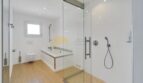 Modernes Badezimmer der Villa in Santa Ponça mit Glasdusche, Badewanne und Holzboden.