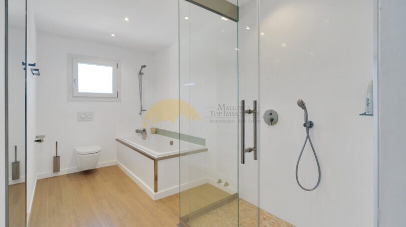 Modernes Badezimmer der Villa in Santa Ponça mit Glasdusche, Badewanne und Holzboden.
