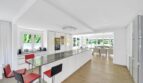 Moderne weiße Küche mit Kochinsel, roten Barhockern und offenem Wohnbereich in Villa Santa Ponça