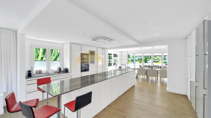 Moderne weiße Küche mit Kochinsel, roten Barhockern und offenem Wohnbereich in Villa Santa Ponça