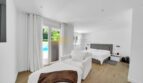 Helles Schlafzimmer der Villa in Santa Ponça mit Holzboden, Doppelbett und Poolblick durch Terrassentür.
