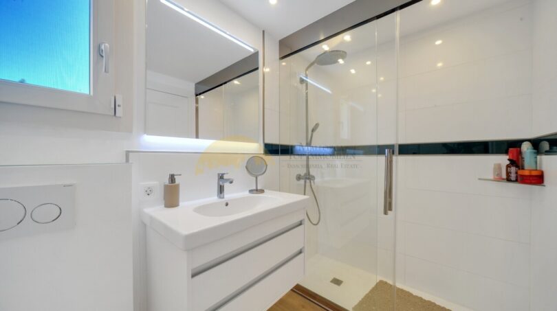 Modernes Badezimmer der Villa in Santa Ponça mit Glasdusche, Waschtisch und Spiegelschrank.