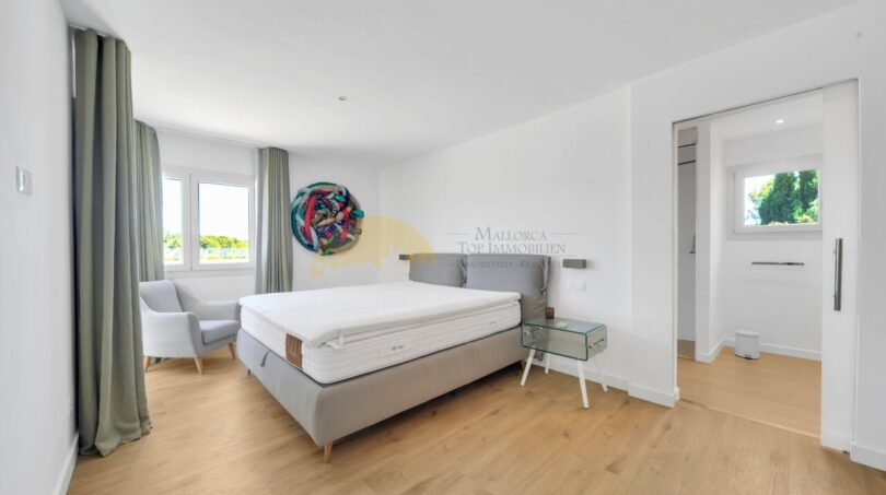 Helles Schlafzimmer der Villa in Santa Ponça mit Doppelbett, Holzboden und Zugang zum Bad.