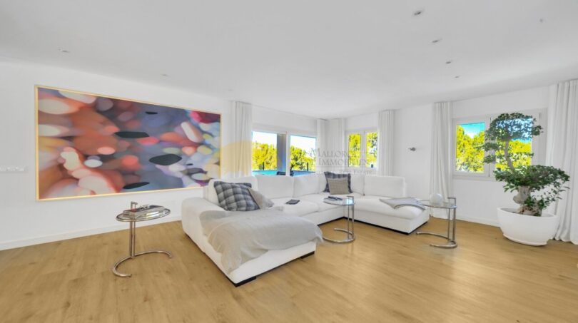 Helles Wohnzimmer mit weißem Sofa, Holzboden und großem Kunstwerk in moderner Villa in Santa Ponça.