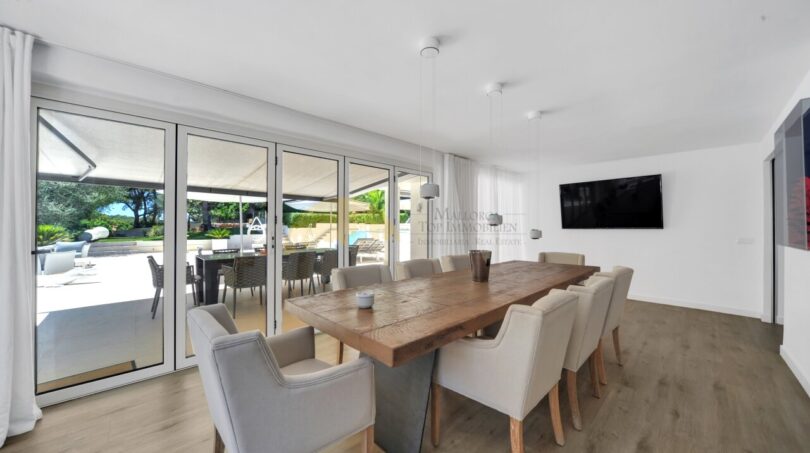 Modernes Esszimmer mit großem Holztisch, Stühlen und Zugang zur Pool-Terrasse der Villa in Santa Ponça.