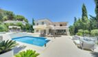 Moderne Villa in Santa Ponça mit Pool, Terrasse, Loungemöbeln und mediterranem Garten unter blauem Himmel.