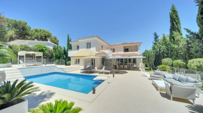Moderne Villa in Santa Ponça mit Pool, Terrasse, Loungemöbeln und mediterranem Garten unter blauem Himmel.