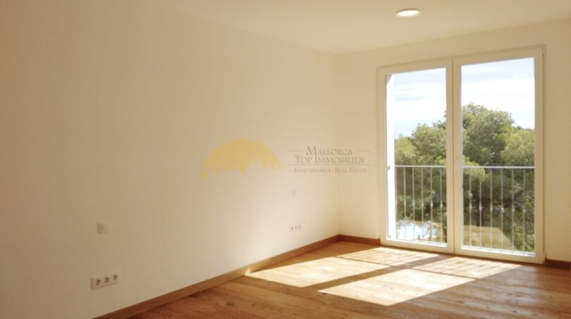 Helles, leeres Zimmer mit Holzboden und Balkon mit Naturblick in Neubau Villa Sol de Mallorca