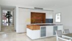 Moderne Einbauküche mit weißen Fronten, Holzakzenten und Kücheninsel in Neubau-Villa Sol de Mallorca