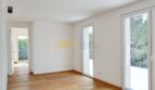 Helles Schlafzimmer der Neubau-Villa in Sol de Mallorca mit Holzboden und zwei Terrassentüren mit Grünblick