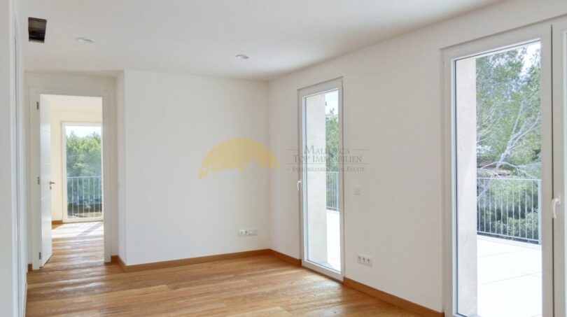 Helles Schlafzimmer der Neubau-Villa in Sol de Mallorca mit Holzboden und zwei Terrassentüren mit Grünblick
