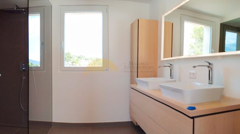 Modernes Badezimmer der Neubau Villa in Sol de Mallorca mit Doppelwaschbecken und ebenerdiger Dusche.