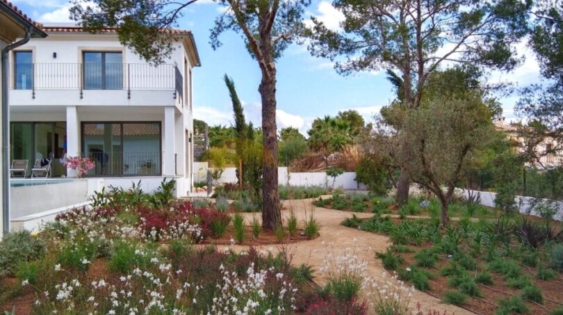Neubau Villa Sol de Mallorca: Mediterraner Garten mit Natursteinweg, Pinien und bunten Blüten