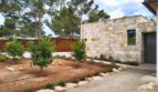 Einfahrt einer Neubau-Villa in Sol de Mallorca mit Natursteinmauer, mediterranem Garten und Pinien