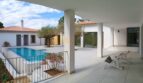 Überdachte Terrasse mit Pool, Liegestühlen und mediterranem Garten der Neubau Villa in Sol de Mallorca