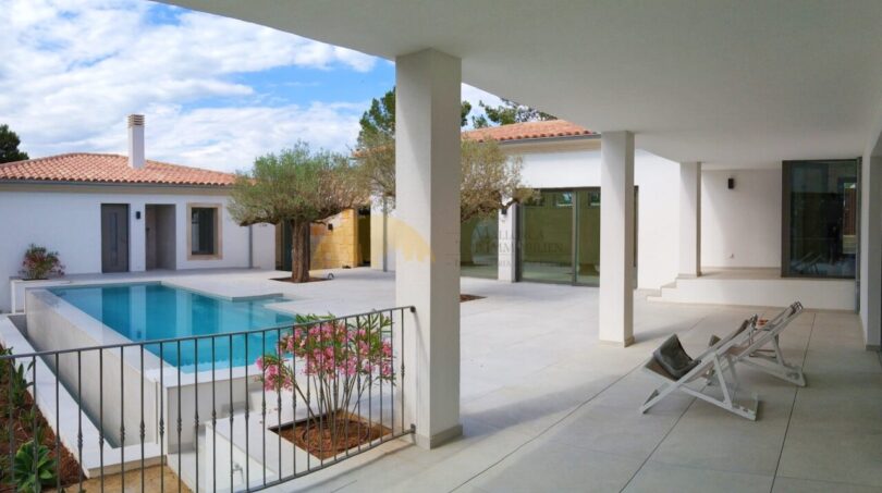 Überdachte Terrasse mit Pool, Liegestühlen und mediterranem Garten der Neubau Villa in Sol de Mallorca