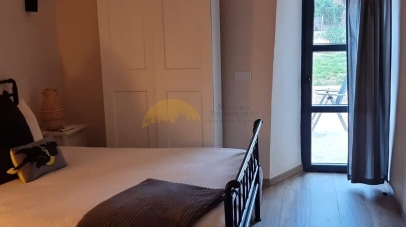 Schlafzimmer der Finca in Felanitx mit Gewölbedecke, Holzboden, Doppelbett und Terrassenzugang.