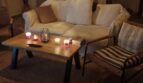 Gemütliches Wohnzimmer der Finca in Felanitx mit weißem Sofa, Kerzen und rustikalen Holzbalken bei Abendstimmung.