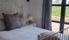 Schlafzimmer der Finca Felanitx mit Gewölbedecke, weißem Eisenbett und Zugang zum Garten