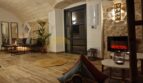 Gemütliches Wohnzimmer der Finca in Felanitx mit Natursteinwänden, Gewölbedecke, Holzboden und modernem Elektrokamin.