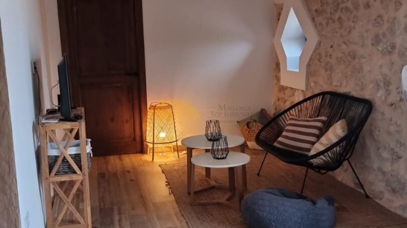 Gewölbtes Wohnzimmer der Finca Felanitx mit Natursteinwänden, Holzboden und mediterranem Boho-Stil