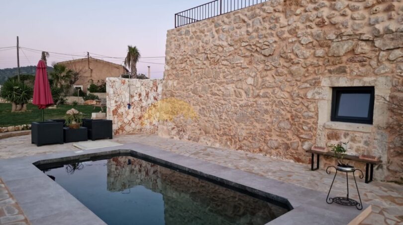 Finca Felanitx: Natursteinhaus mit rechteckigem Pool, Terrasse und Lounge-Bereich im Abendlicht