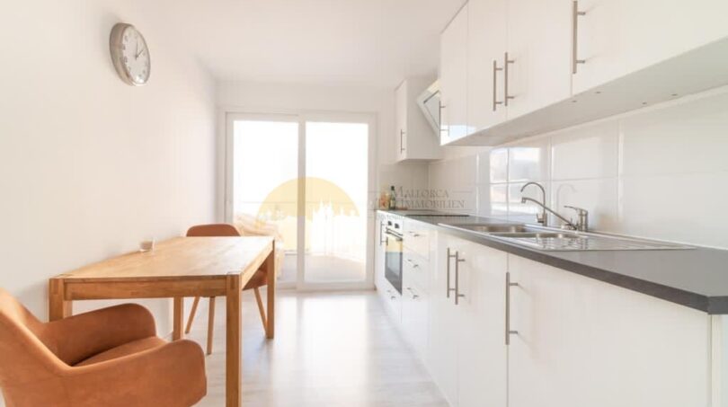 Helle modernisierte Küche mit Essbereich, weißen Einbauschränken und Balkonzugang in zentraler Wohnung im Arenal, Palma