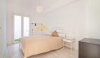 Helles Schlafzimmer mit Doppelbett, weißen Wänden, Holzboden und Balkonzugang in modernisierter Wohnung im Arenal.