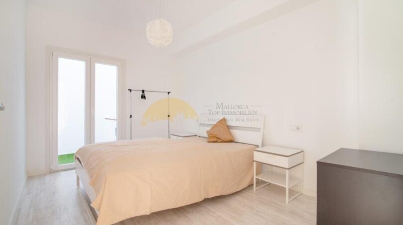 Helles Schlafzimmer mit Doppelbett, weißen Wänden, Holzboden und Balkonzugang in modernisierter Wohnung im Arenal.