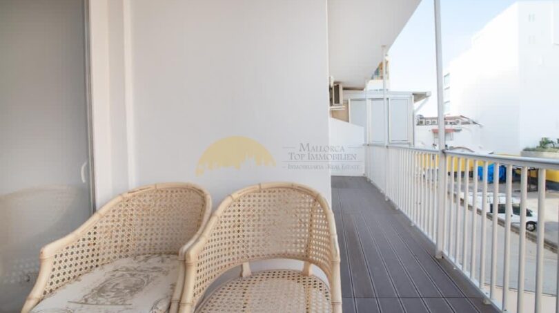 Balkon der modernisierten Wohnung in Arenal mit zwei Rattanstühlen und Blick auf die Umgebung.