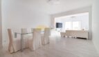 Helles Wohn- und Esszimmer mit Glasstisch, weißen Stühlen und modernem TV in zentraler Wohnung in Arenal, Palma