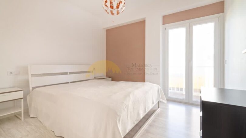 Helles Schlafzimmer mit Doppelbett, weißen Möbeln, Parkettboden und Balkonzugang in modernisierter Wohnung in Arenal, Palma.