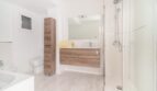 Modernes Badezimmer der Wohnung in Arenal mit Glasdusche, Holzunterschrank, Spiegel und WC.