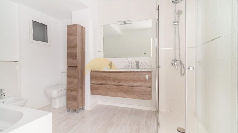 Modernes Badezimmer der Wohnung in Arenal mit Glasdusche, Holzunterschrank, Spiegel und WC.