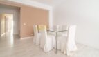 Helles Esszimmer mit Glastisch und weißen Stühlen, Laminatboden und Durchgang zum Flur in modernisierter Wohnung in Arenal.