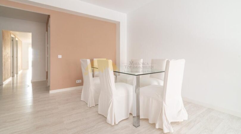 Helles Esszimmer mit Glastisch und weißen Stühlen, Laminatboden und Durchgang zum Flur in modernisierter Wohnung in Arenal.