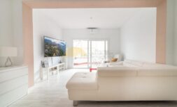 Helles Wohnzimmer mit weißem Ledersofa, TV und Zugang zur Terrasse in modernisierter Wohnung in Arenal