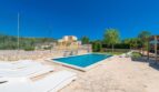 Finca Son Macià: Außenbereich mit Pool, weißen Liegestühlen, Steinpflaster, Tennisplatz und Pergola unter blauem Himmel.