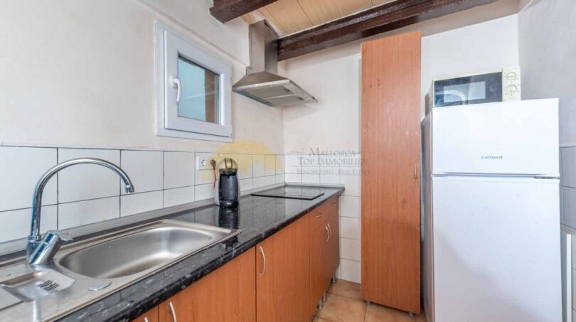 Rustikale Küche der Finca in Son Macià mit Holzbalken, Granitarbeitsplatte und modernen Geräten.
