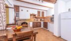 Rustikale Küche der Finca Son Macià mit Holzmöbeln, Kamin, Terrakottaboden und mediterranem Charme.